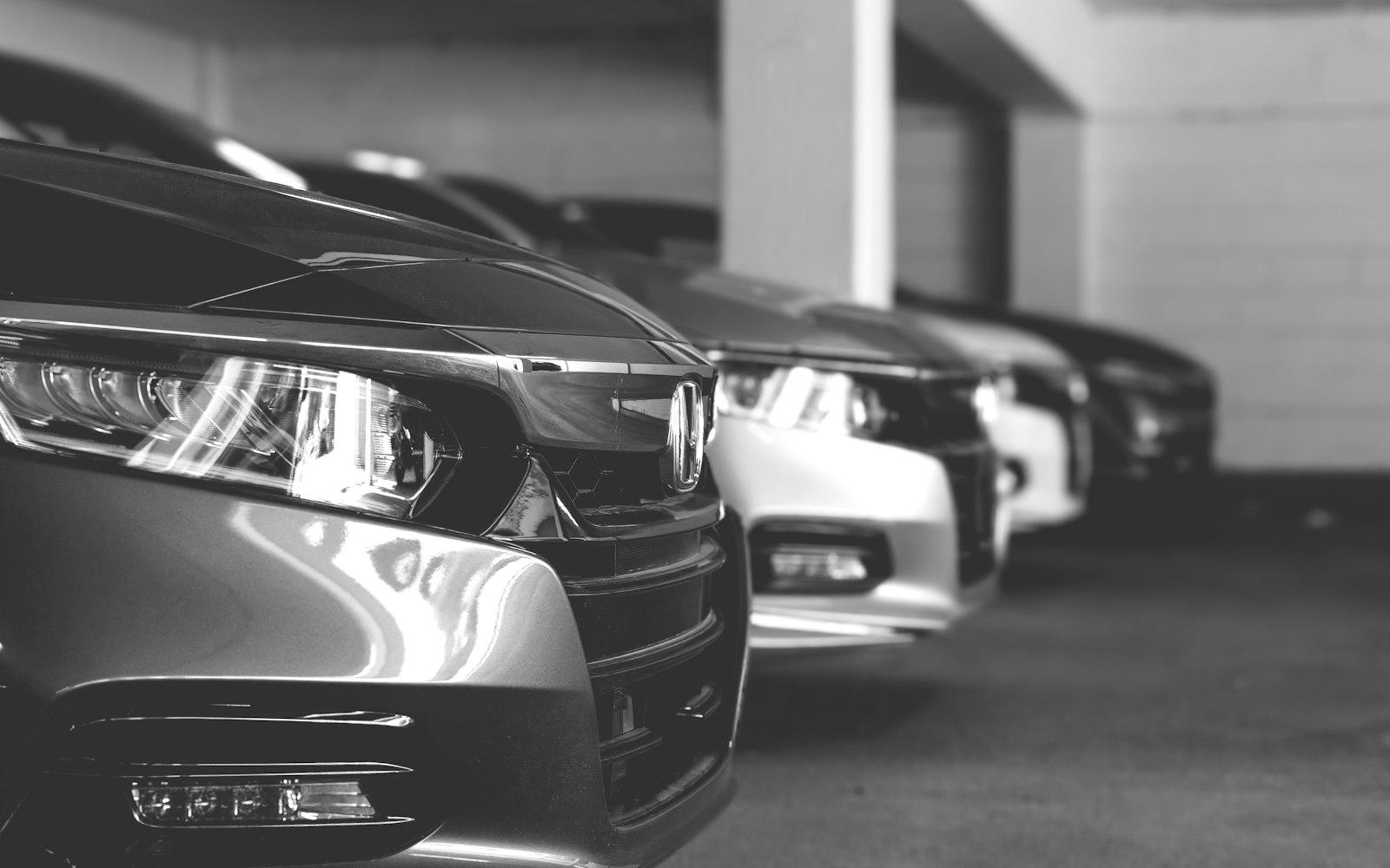 A line of dark vehicles parked under low showroom lighting.