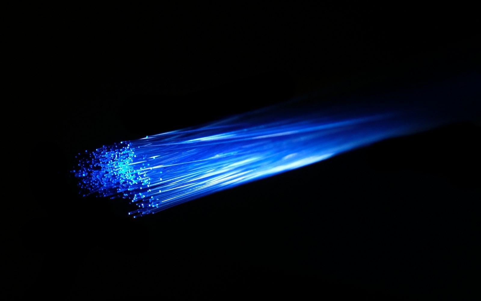 Illuminated fibre-optic strands against a black background.